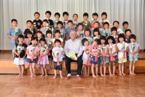 バラを嬉しそうに持つ園児と外山会長(中央)