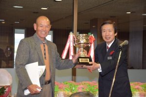 名倉組合長から優勝カップを受け取る勝野さん(左)