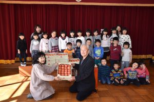 離島保育園の園児たちにトマトを贈る斉藤部会長(前列右)