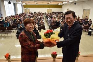 代表者に鉢花を手渡す名倉組合長(右)