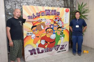 本店ホールに展示されたたて看板と斉藤部長(左)