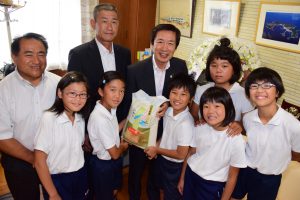 米を贈るJAの名倉組合長(後列中央)と佐久島小5・6年生の児童ら、佐久島小の黒柳校長(後列左2人目)、佐久島中の牧野校長(後列左端)