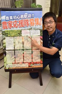 「農家応援隊募集」のポスターと園芸販売課の担当者