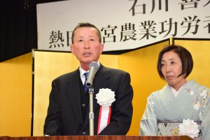 檀上で謝辞を述べる石川喜久雄さんと千賀子夫人