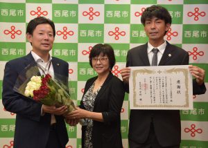 中村市長(左)に今週のバラを贈る若山事務長(中央)と感謝状を受け取った稲垣組合長(右)