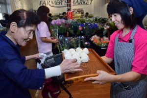 来店者におにぎりを手渡す生産者の女性