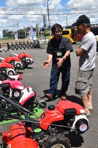 農機の使用方法を案内する岡田所長(左)